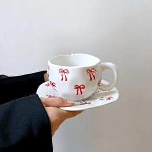 فنجان مع صحن مزخرف بالفيونكات الحمراء